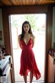 A woman in a red dress standing in a kitchen.