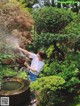 A woman is spraying water from a hose in a garden.