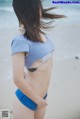 A woman standing on a beach with her back to the camera.
