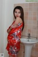 A woman in a red kimono standing in front of a sink.