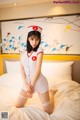 A woman in a nurse outfit sitting on a bed.