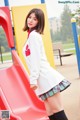 A woman in a school uniform standing on a playground slide.