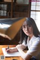 A woman sitting at a table writing in a notebook.