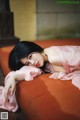 A woman in a pink dress laying on a red couch.