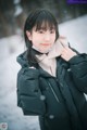 A woman wearing a black jacket and a scarf in the snow.