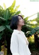 A woman standing in front of a banana tree.