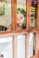 A woman looking out of a window at the camera.