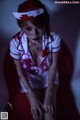 A woman dressed as a nurse with blood on her face.