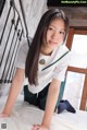 A young woman in a school uniform is posing on a bed.