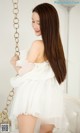 A woman in a white dress sitting on a swing.