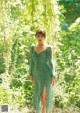 A woman in a green dress standing in the woods.