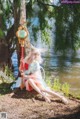 A woman sitting on the ground next to a body of water.