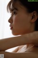 A woman sitting in front of a window with her hand on her chin.