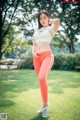 A woman in a white top and orange leggings posing for a picture.