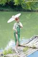 A woman in a green dress holding an umbrella.