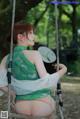 A woman in a green dress sitting on a swing.