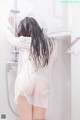 A woman standing in a shower with her back to the camera.