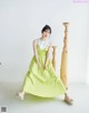 A woman in a green dress sitting on a wooden chair.