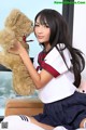 A woman in a school uniform holding a teddy bear.