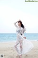 A woman in a white dress standing on a beach.