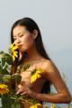 A naked woman standing in a field of sunflowers.