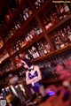 A woman in a blue dress standing in front of a bar.