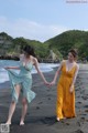 Two women walking on a beach holding hands. 