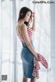 A woman in a red and white striped top and blue denim skirt.