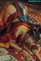 A woman in a red and gold outfit laying on a rug.